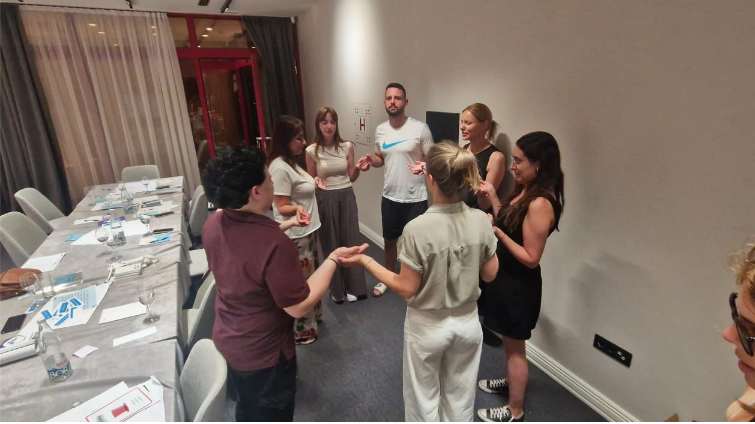 Učesnici obuke stoje u krugu u sali za sastanke i učestvuju u interaktivnoj grupnoj vježbi.