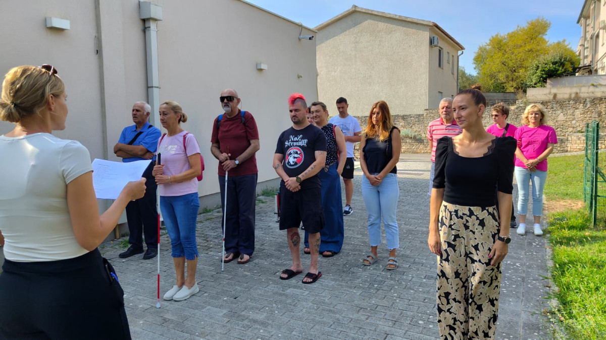 Grupa učesnika iz Hrvatske stoji na otvorenom u redu i sluša osobu koja vodi radionicu.