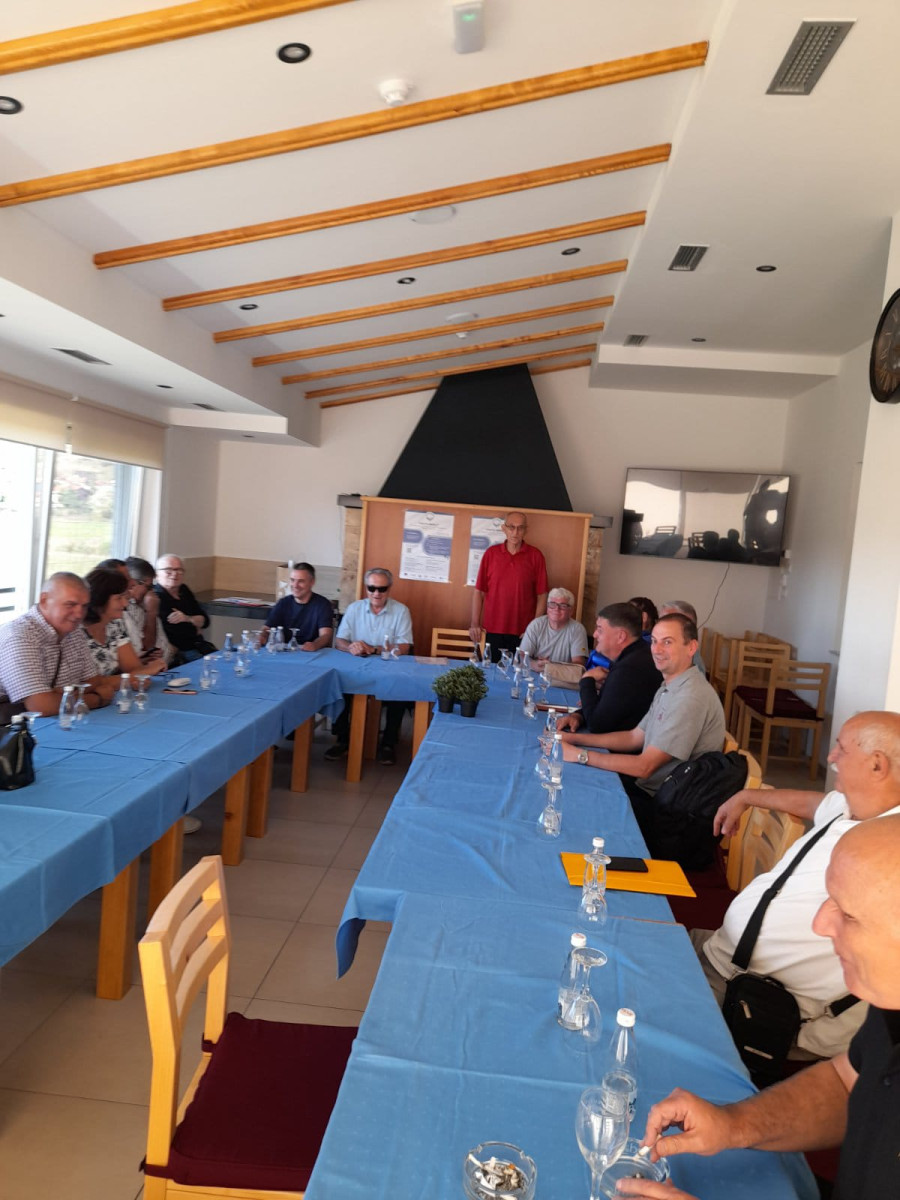 Grupa učesnika iz Bosne sjedi za stolovima u zatvorenom prostoru i učestvuje na radionici.